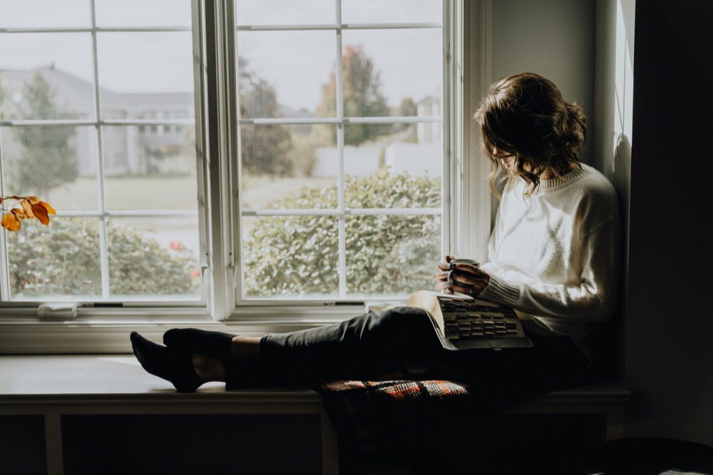 A woman sitting in a window seat, reading